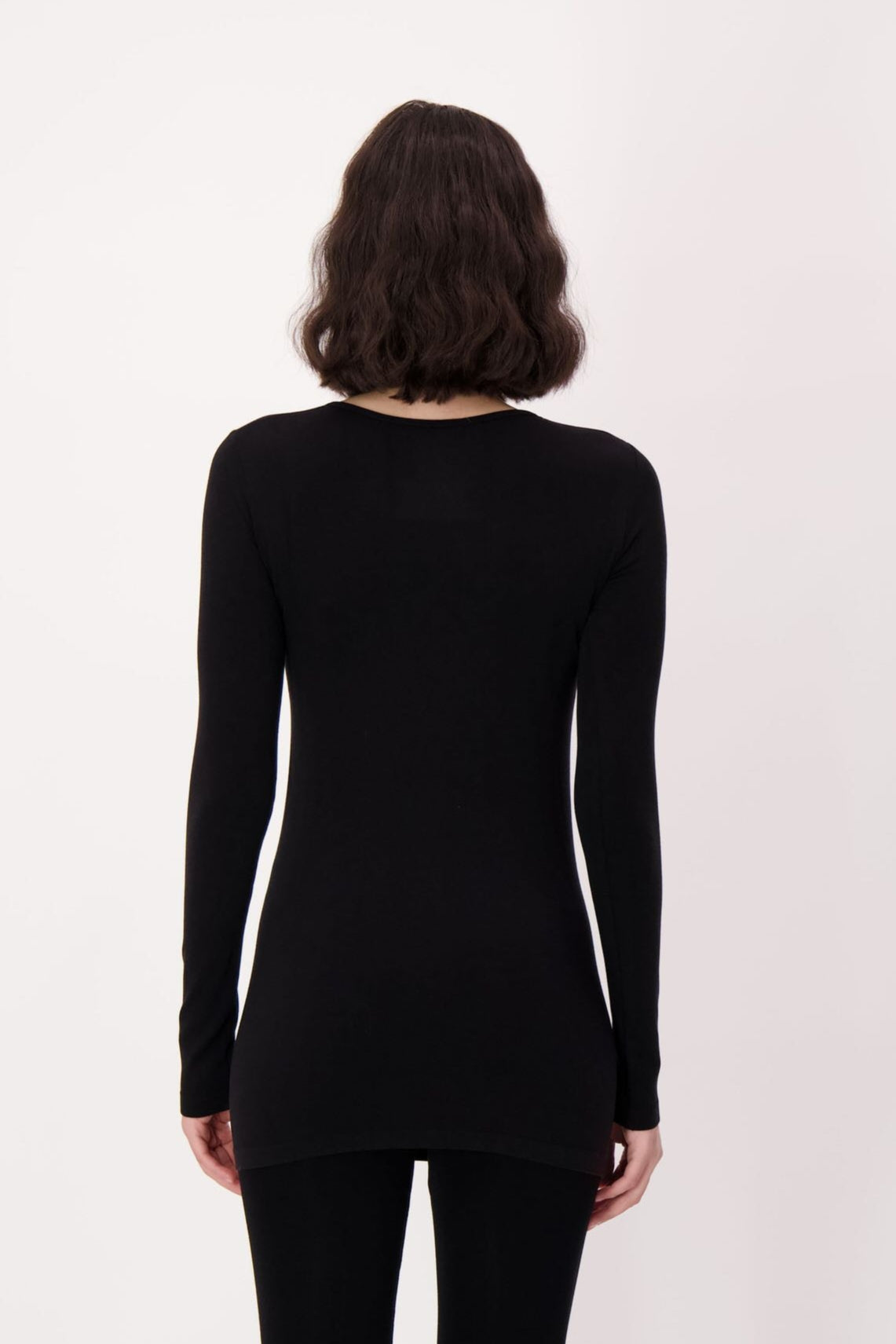 Person wearing a black long-sleeve top and leggings on a white background
