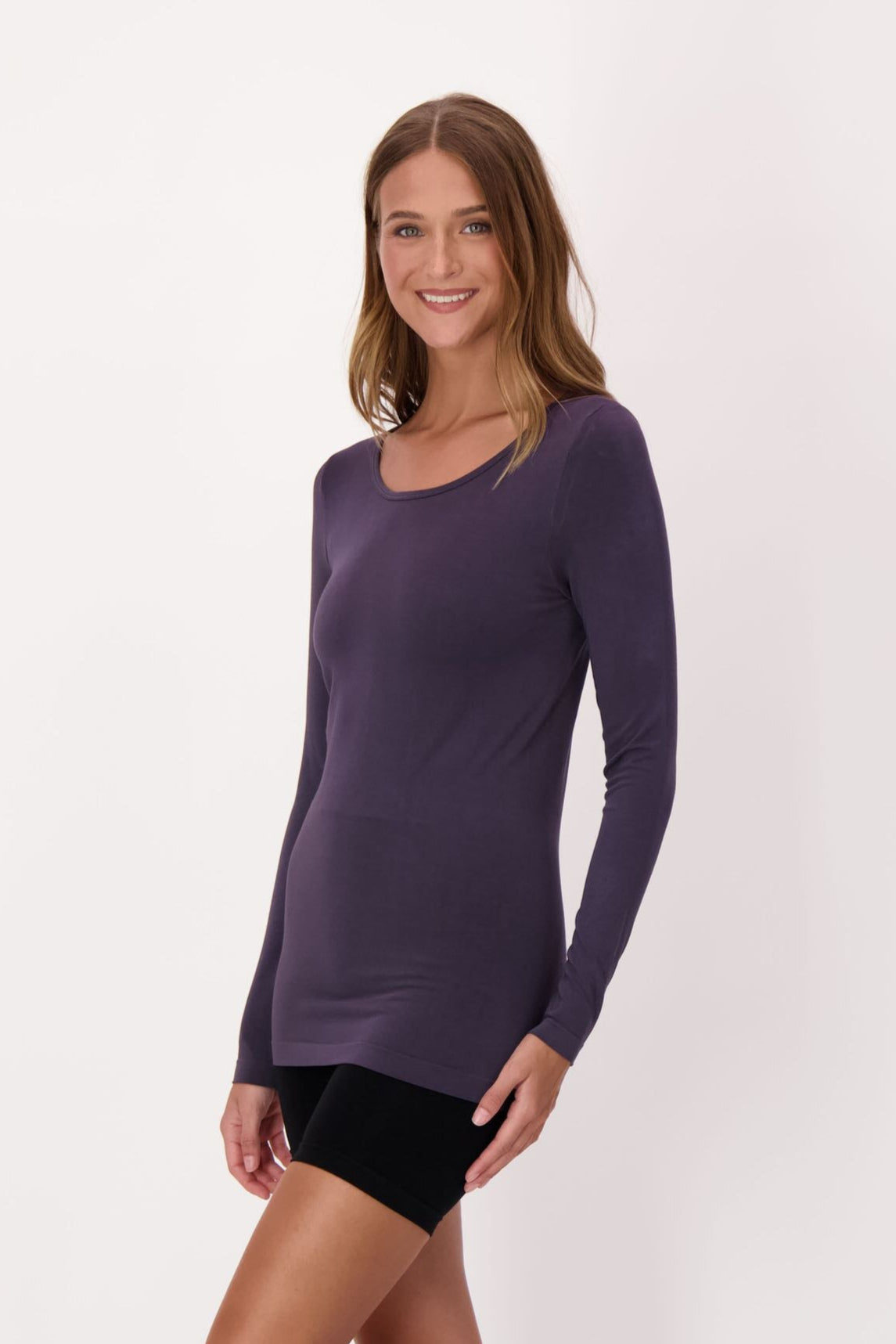 Woman wearing a long-sleeve purple top and black shorts on a white background
