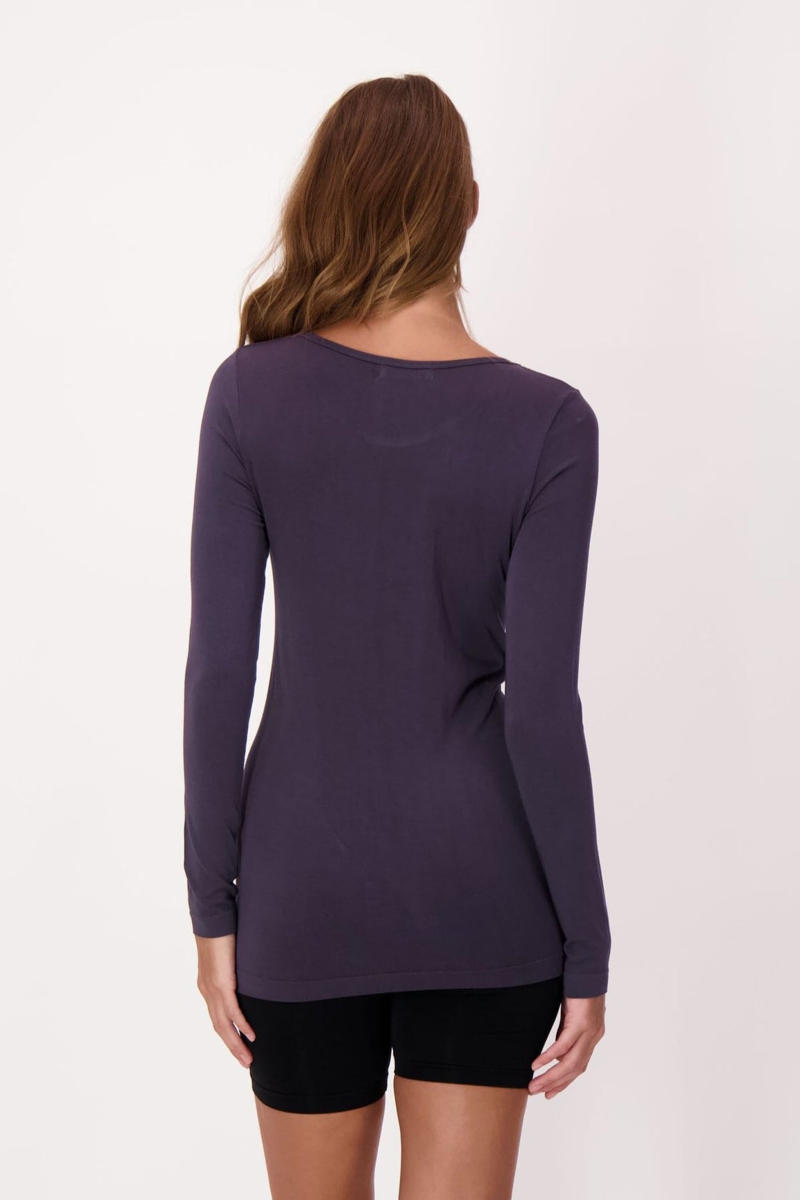 Person wearing a long-sleeve purple top and black shorts on a white background