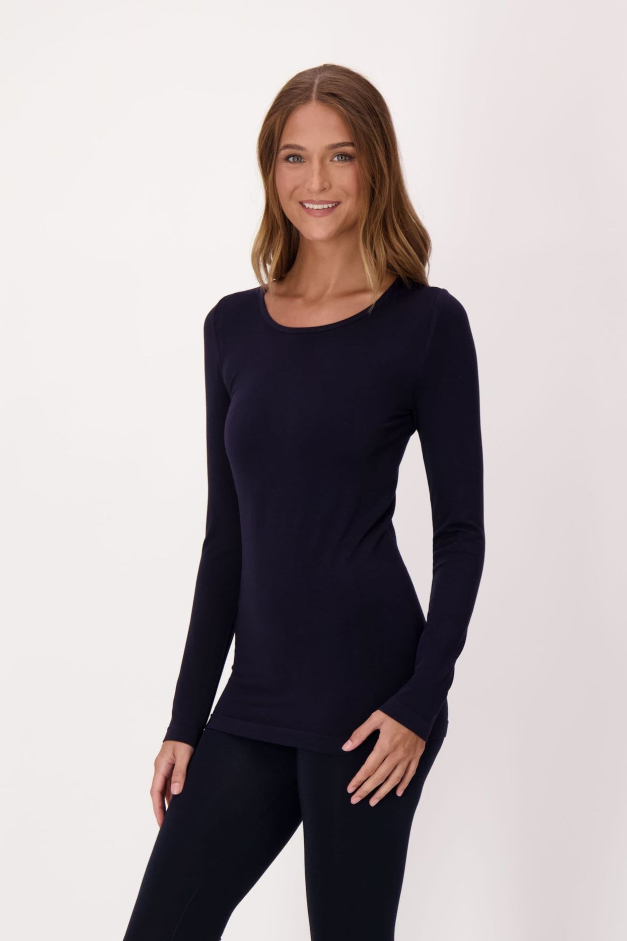 Woman wearing a black long-sleeve top and capri leggings on a white background