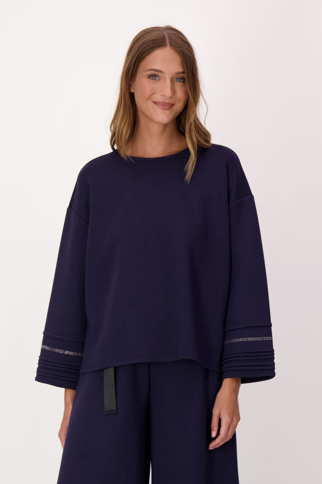Woman wearing a navy outfit with wide-leg pants on a white background